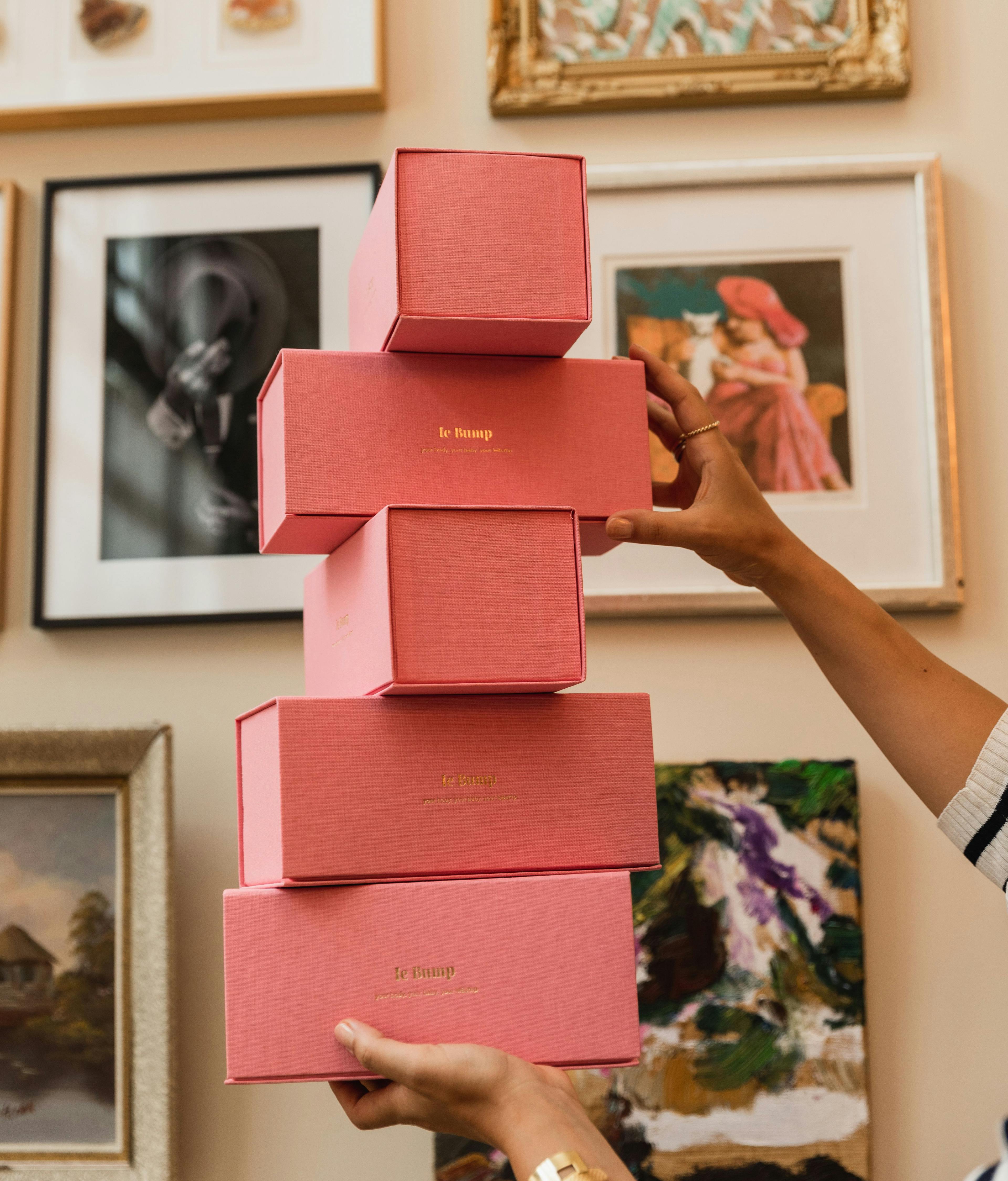 Op elkaar gestapelde roze cadeaudozen van le Bump voor babyshower cadeau